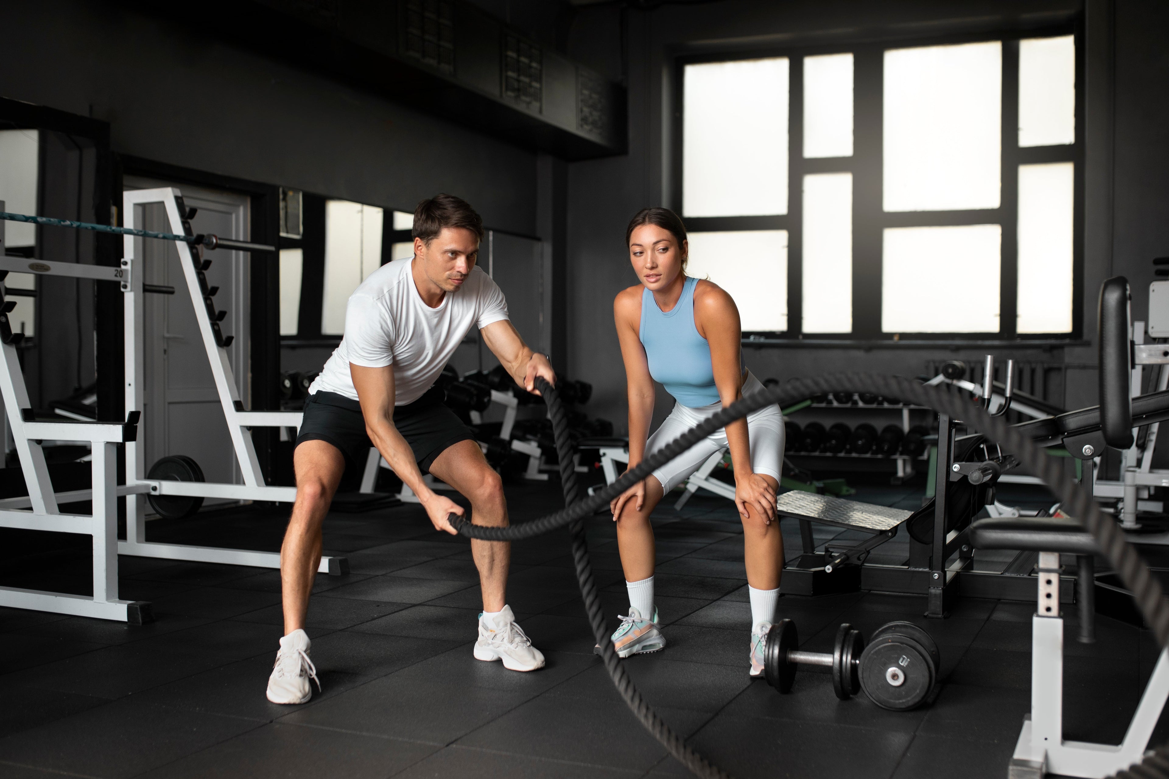 Two people training with battle ropes in a modern gym featuring durable eco-friendly flooring.